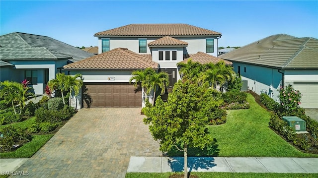 mediterranean / spanish-style home featuring a tile roof, decorative driveway, a garage, and stucco siding