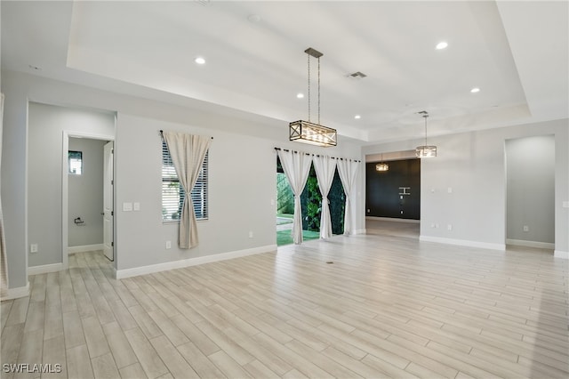 spare room with recessed lighting, visible vents, a raised ceiling, and light wood-style floors