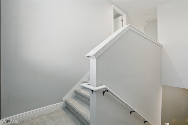 staircase featuring baseboards and carpet flooring