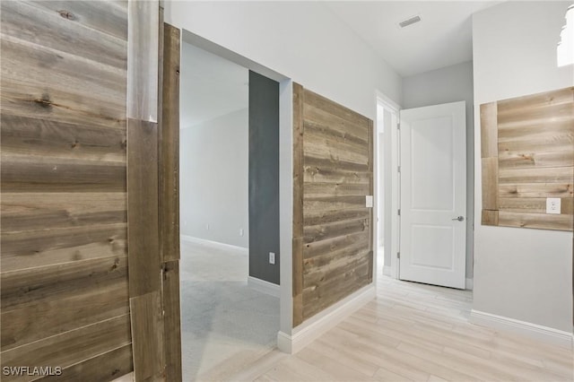 hallway featuring light wood-style flooring, baseboards, and visible vents