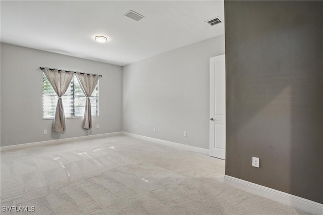 spare room with baseboards, visible vents, and light carpet