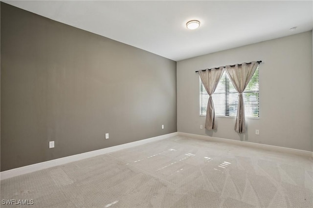 spare room with light colored carpet and baseboards