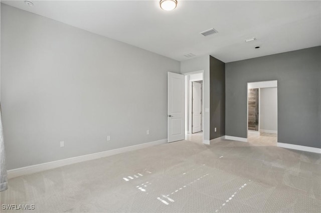 empty room with visible vents, baseboards, and light colored carpet