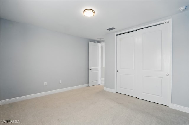 unfurnished bedroom featuring baseboards, visible vents, a closet, and light carpet