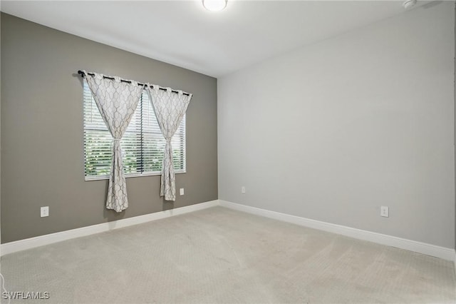 spare room with light colored carpet and baseboards