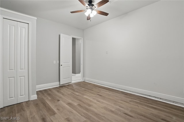 unfurnished bedroom featuring wood finished floors, baseboards, a closet, and ceiling fan