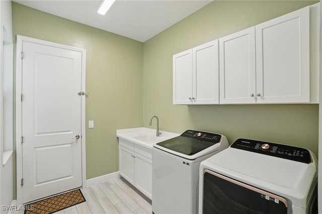 washroom featuring a sink, baseboards, cabinet space, and independent washer and dryer