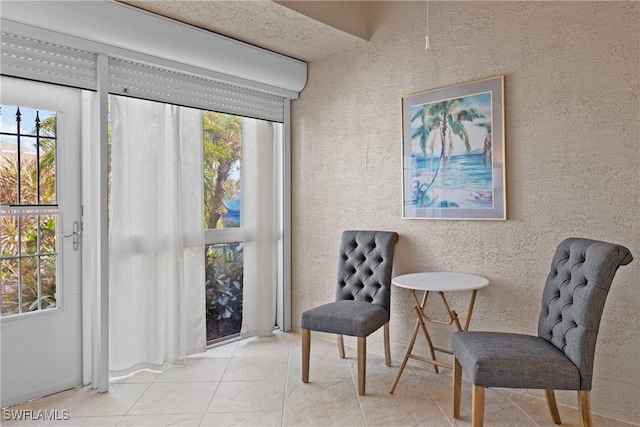 sitting room featuring a healthy amount of sunlight, tile patterned flooring, and a textured wall