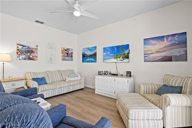 living area with visible vents, a ceiling fan, and wood finished floors