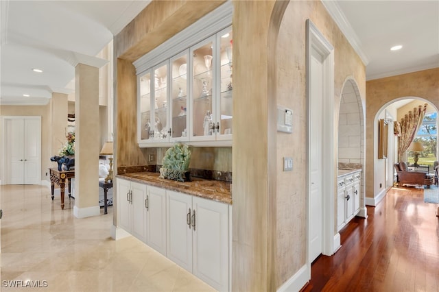 bar featuring recessed lighting, baseboards, arched walkways, and crown molding