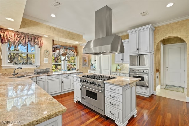 kitchen featuring visible vents, crown molding, light stone countertops, appliances with stainless steel finishes, and island range hood