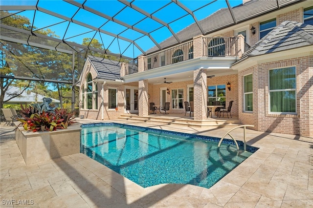 pool with a ceiling fan, a patio, glass enclosure, and french doors