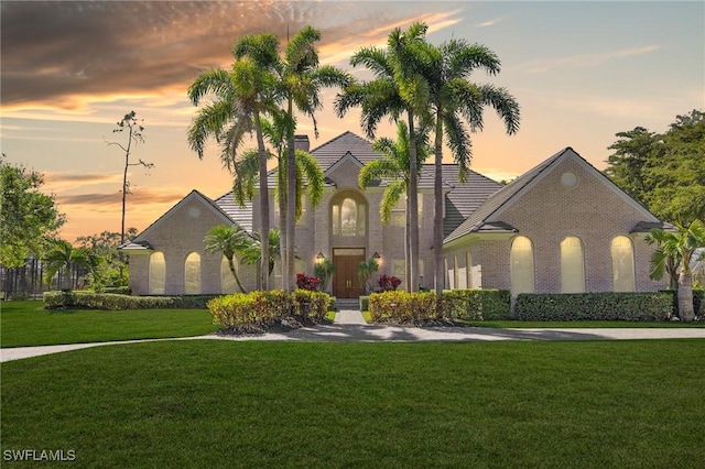 view of front of home featuring a tile roof, a front yard, and brick siding