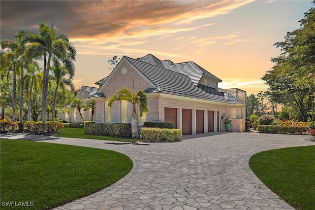 view of front of house with a front lawn, a garage, brick siding, and curved driveway