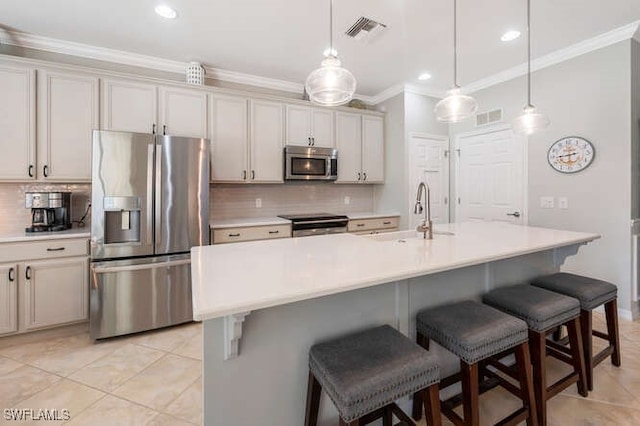 kitchen featuring visible vents, crown molding, appliances with stainless steel finishes, a kitchen breakfast bar, and a sink