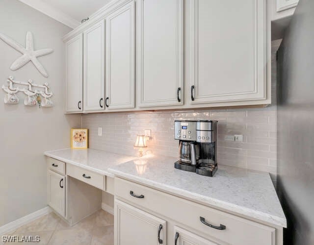 kitchen with light tile patterned flooring, light stone countertops, tasteful backsplash, and baseboards