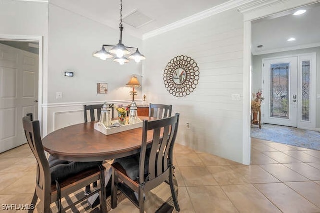 dining space featuring a wainscoted wall, an inviting chandelier, ornamental molding, and light tile patterned flooring