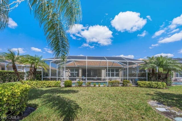 rear view of property with glass enclosure and a lawn