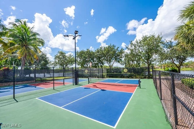 view of tennis court with community basketball court and fence