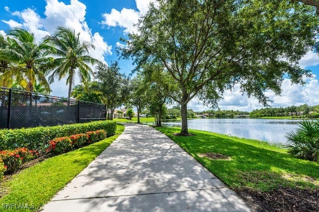 view of community with fence, a yard, and a water view