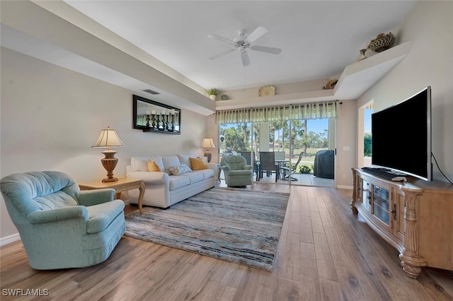 living area featuring a ceiling fan, wood finished floors, visible vents, and baseboards