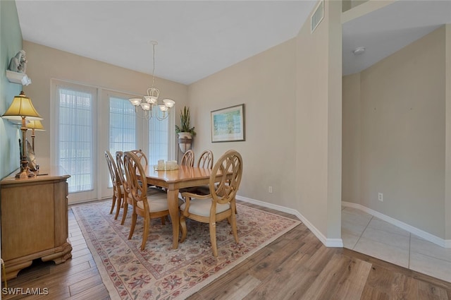 dining area featuring visible vents, baseboards, light wood-style floors, and a chandelier