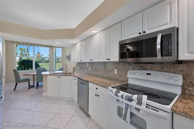 kitchen with tasteful backsplash, light tile patterned floors, appliances with stainless steel finishes, white cabinetry, and a sink