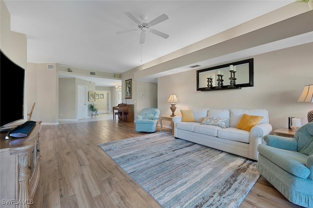 living room featuring baseboards, wood finished floors, visible vents, and ceiling fan