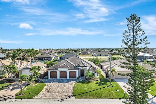 view of front of house with decorative driveway, a front yard, an attached garage, and a residential view