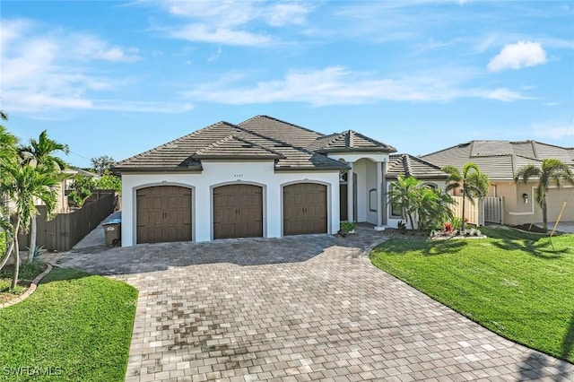 view of front of home with stucco siding, decorative driveway, fence, a front yard, and a garage