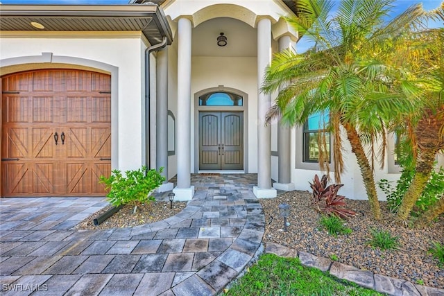 view of exterior entry featuring stucco siding and a garage