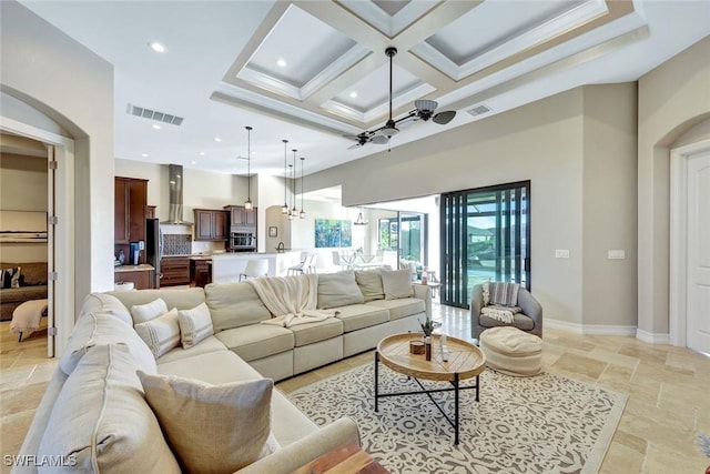 living room featuring stone tile floors, baseboards, visible vents, and coffered ceiling