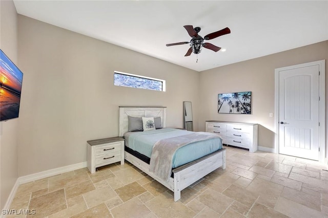 bedroom with stone tile flooring, a ceiling fan, and baseboards