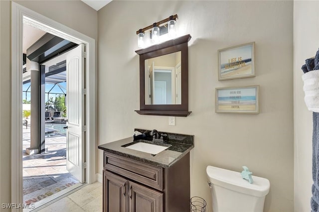 half bath featuring vanity, toilet, and stone tile flooring