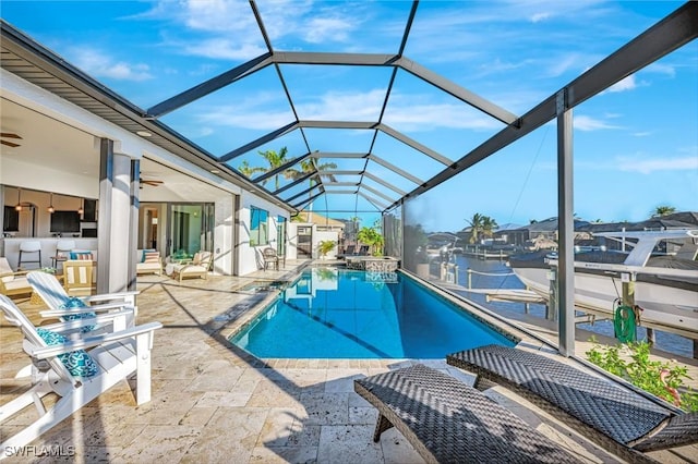 view of swimming pool with a patio area, glass enclosure, a pool with connected hot tub, and a ceiling fan