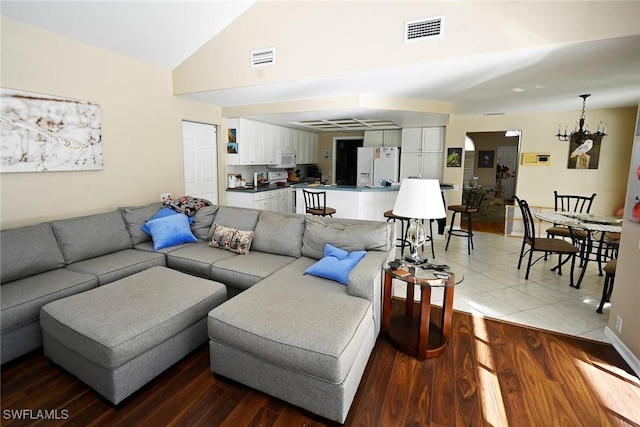 living area featuring visible vents, wood finished floors, and vaulted ceiling