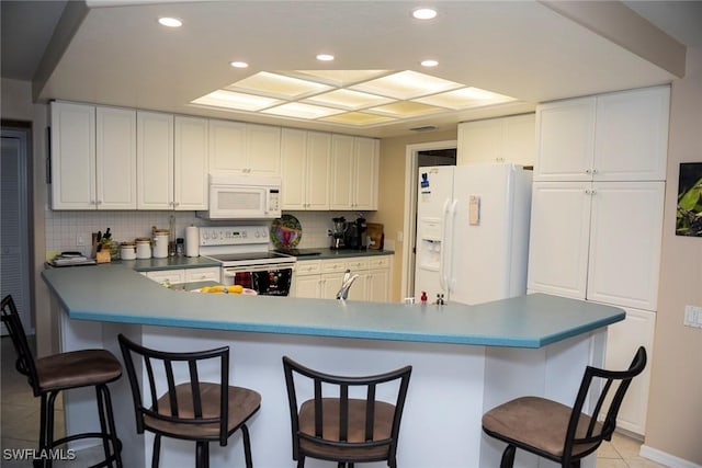 kitchen featuring tasteful backsplash, recessed lighting, white appliances, a breakfast bar area, and light tile patterned floors