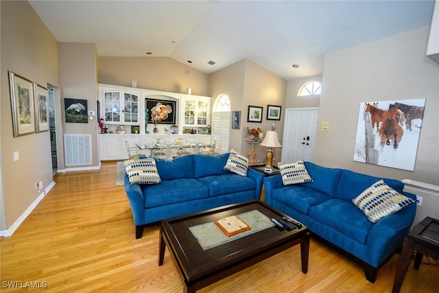 living area featuring visible vents, baseboards, light wood-type flooring, and lofted ceiling