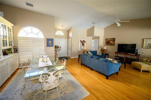 dining room featuring light wood-type flooring, visible vents, high vaulted ceiling, and ceiling fan