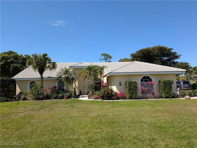 view of front of property with stucco siding, a front yard, and a tiled roof