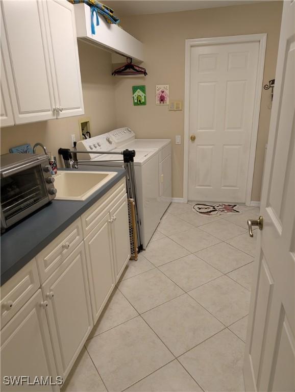 laundry room featuring independent washer and dryer, light tile patterned floors, cabinet space, and baseboards