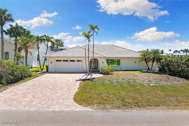 single story home featuring a front lawn, an attached garage, driveway, and stucco siding