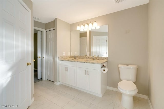 bathroom with toilet, marble finish floor, a sink, double vanity, and baseboards