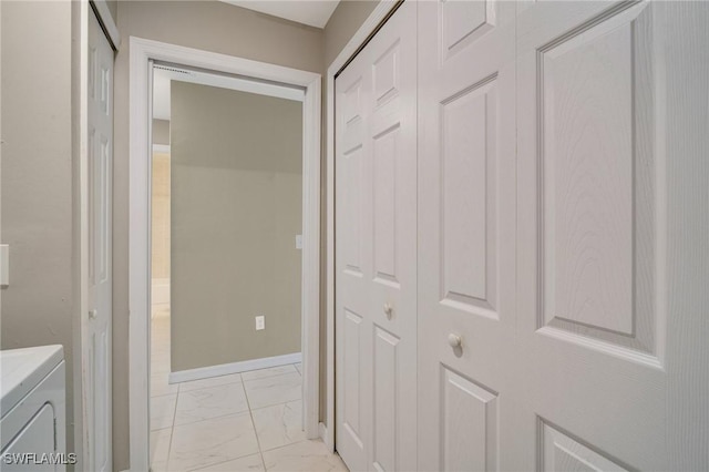 hallway with washer and clothes dryer, marble finish floor, and baseboards