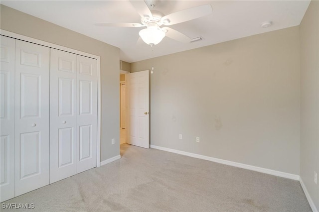 unfurnished bedroom featuring a ceiling fan, light colored carpet, a closet, and baseboards