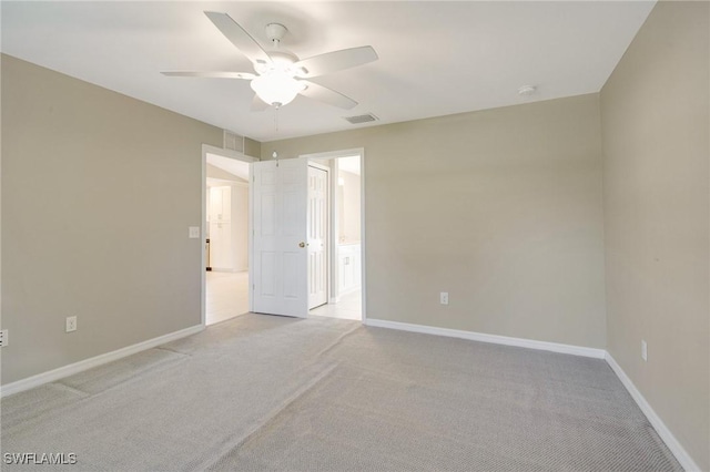 spare room with baseboards, light colored carpet, visible vents, and ceiling fan