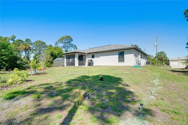 rear view of house featuring stucco siding and a yard