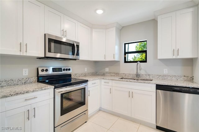 kitchen featuring white cabinets, light stone counters, appliances with stainless steel finishes, and a sink