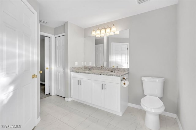 bathroom with toilet, marble finish floor, a sink, double vanity, and baseboards