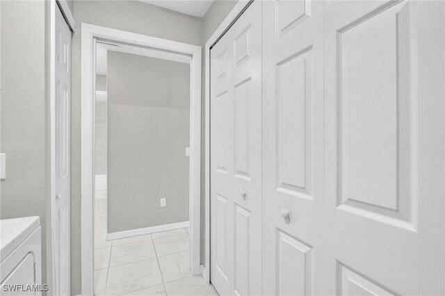 corridor featuring independent washer and dryer, marble finish floor, and baseboards